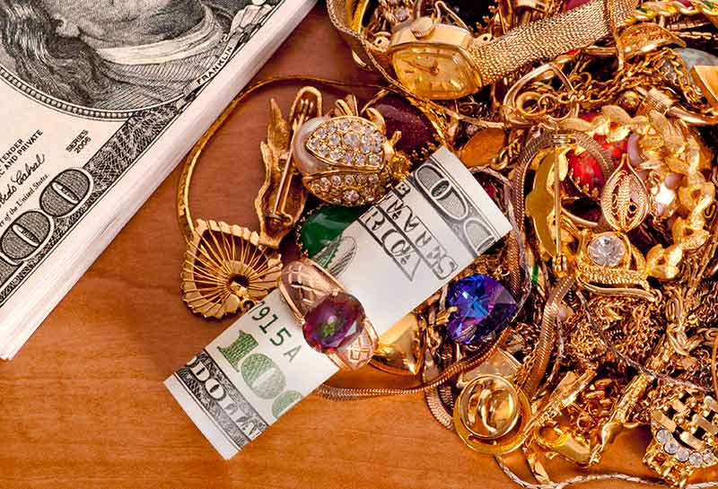 gold jewelry piled up next to hundreds of dollars